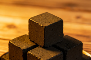 Tumpukan briket arang batok kelapa kualitas ekspor hasil produksi Indonesian charcoal briquette supplier profesional di pabrik.