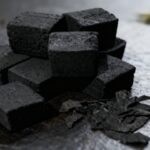 Tumpukan eco-friendly charcoal briquettes berbentuk kubus dari tempurung kelapa untuk keperluan ekspor dan bahan bakar BBQ.