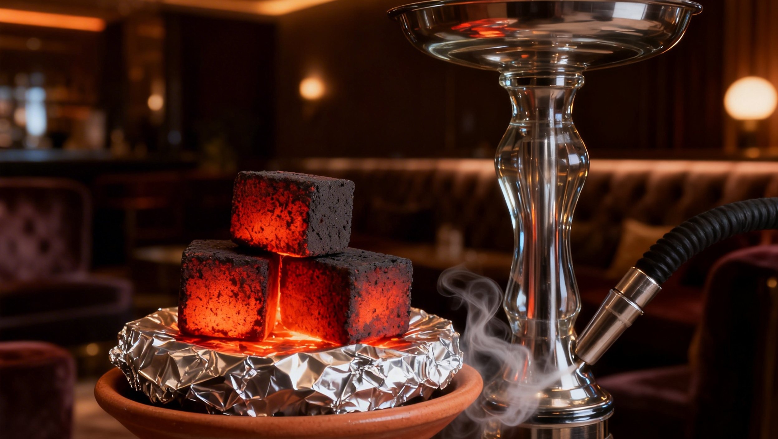 Tumpukan arang briket shisha berbentuk kubus dari tempurung kelapa yang membara merah di atas tungku shisha.